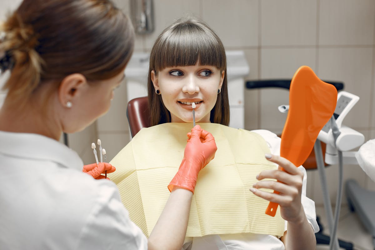 Dentist shade-matching porcelain veneers with a patient before a smile makeover